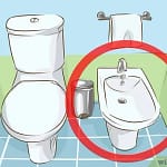 Illustration of a bidet and toilet setup in a bathroom with a towel rack.