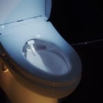 Close-up view of a modern toilet bowl featuring a bidet attachment.