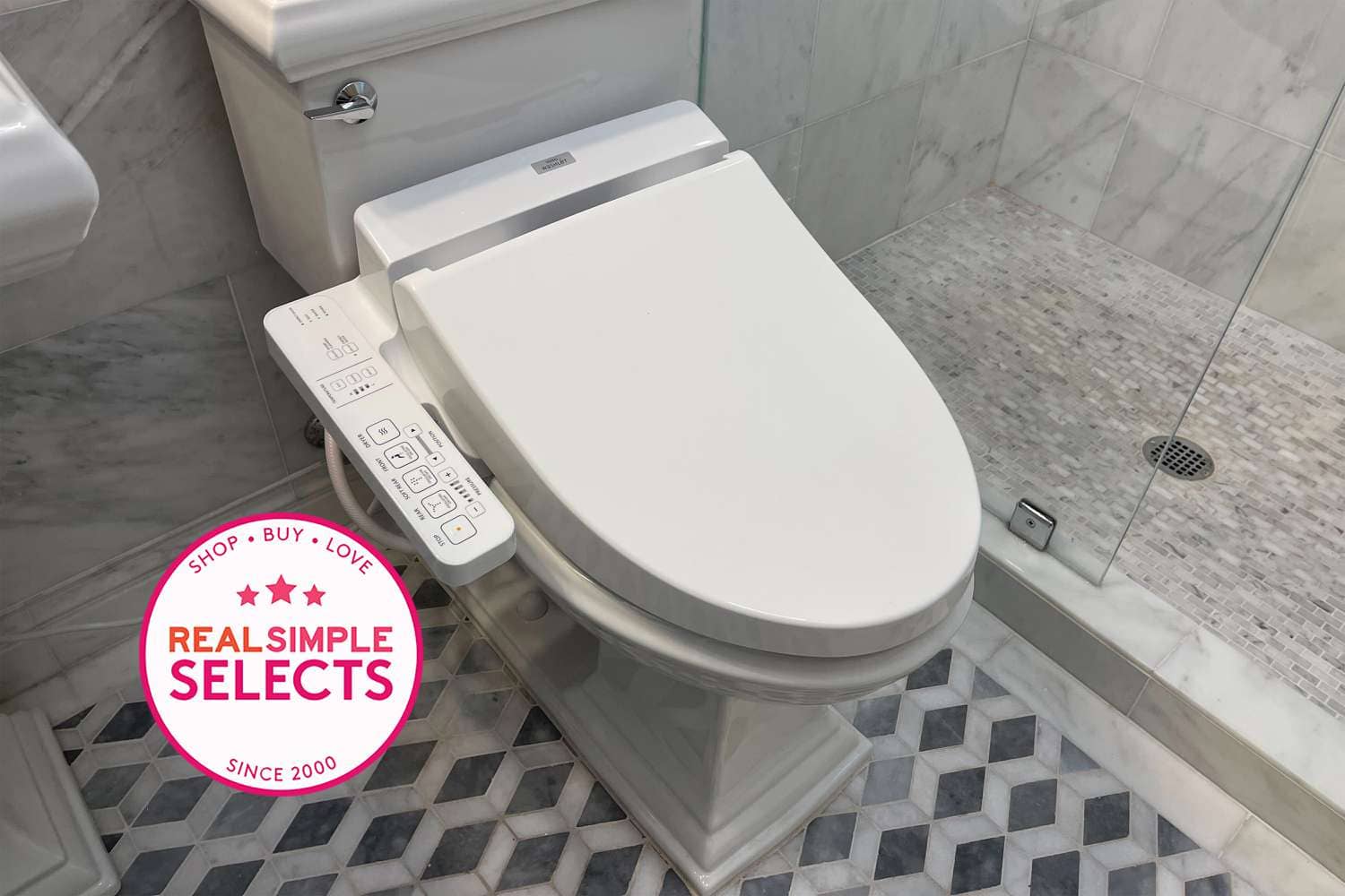 White bidet toilet seat with a control panel on the side in a bathroom setting.