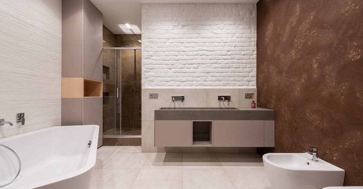 Contemporary bathroom featuring a bathtub, shower, and dual sink vanity with a textured wall.