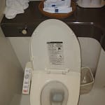 White bidet toilet seat with a control panel on the side and an open lid.