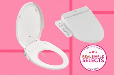 White bidet toilet seat with a remote control on a pink background.