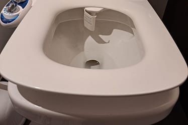 Close-up view of a white toilet featuring a bidet attachment on the side.