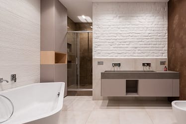 Contemporary bathroom featuring a bathtub, shower, and dual sink vanity with a textured wall.