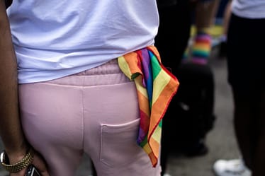 Individual wearing a rainbow bandana tied at the waist during a public event.