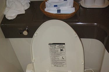 White bidet toilet seat with a control panel on the side and an open lid.