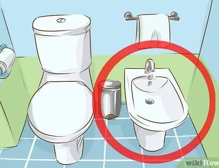 Illustration of a bidet and toilet setup in a bathroom with a towel rack.