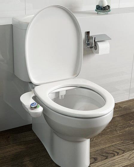 A white bidet toilet seat with a control panel on the side, positioned in a bathroom setting.