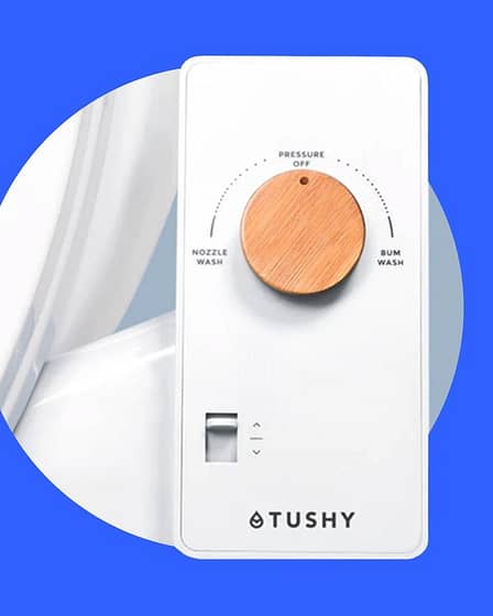 TUSHY bidet attachment installed on a toilet with a control panel for water pressure adjustment.