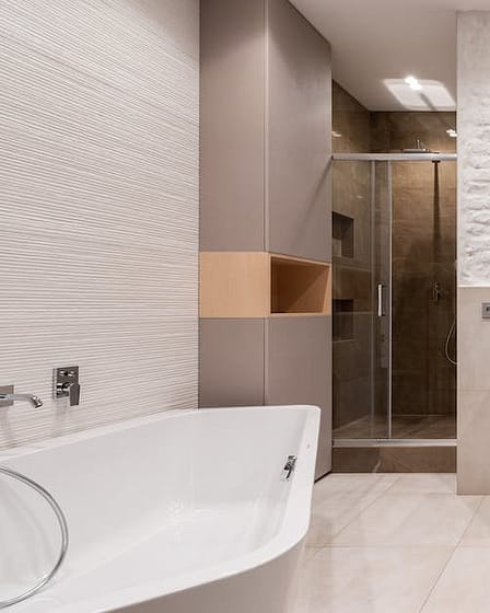 Contemporary bathroom featuring a bathtub, shower, and dual sink vanity with a textured wall.