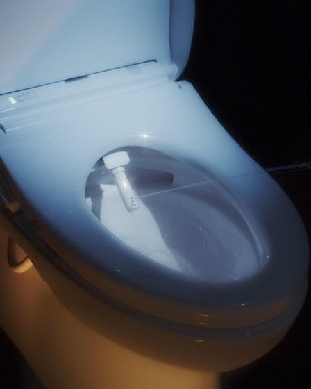 Close-up view of a modern toilet bowl featuring a bidet attachment.