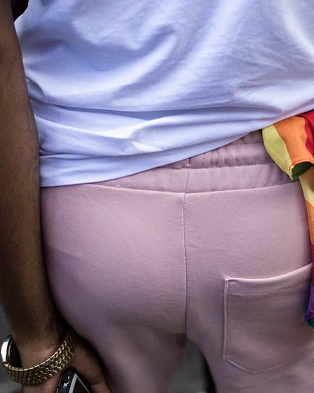 Individual wearing a rainbow bandana tied at the waist during a public event.