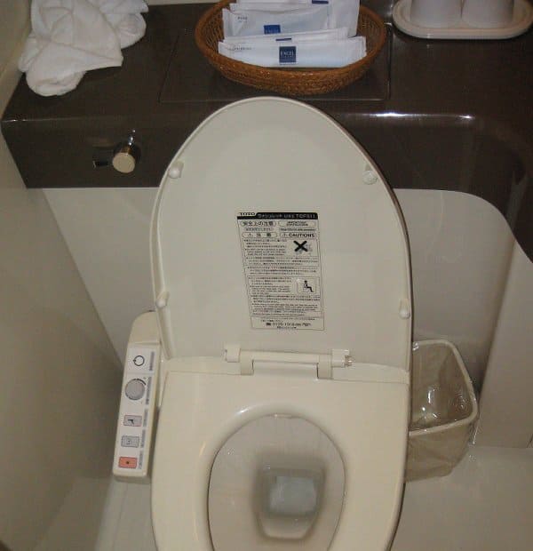 White bidet toilet seat with a control panel on the side and an open lid.