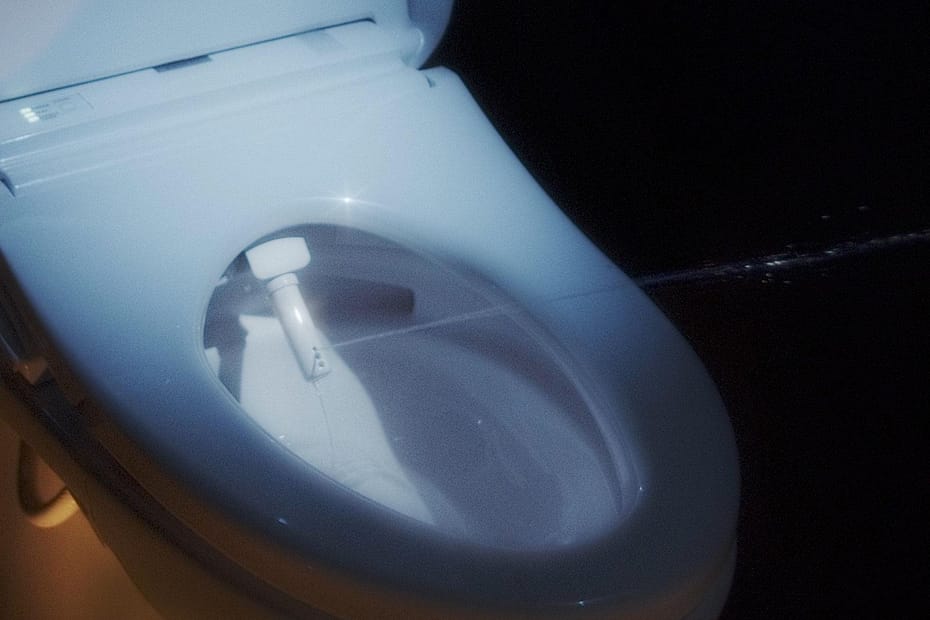 Close-up view of a modern toilet bowl featuring a bidet attachment.